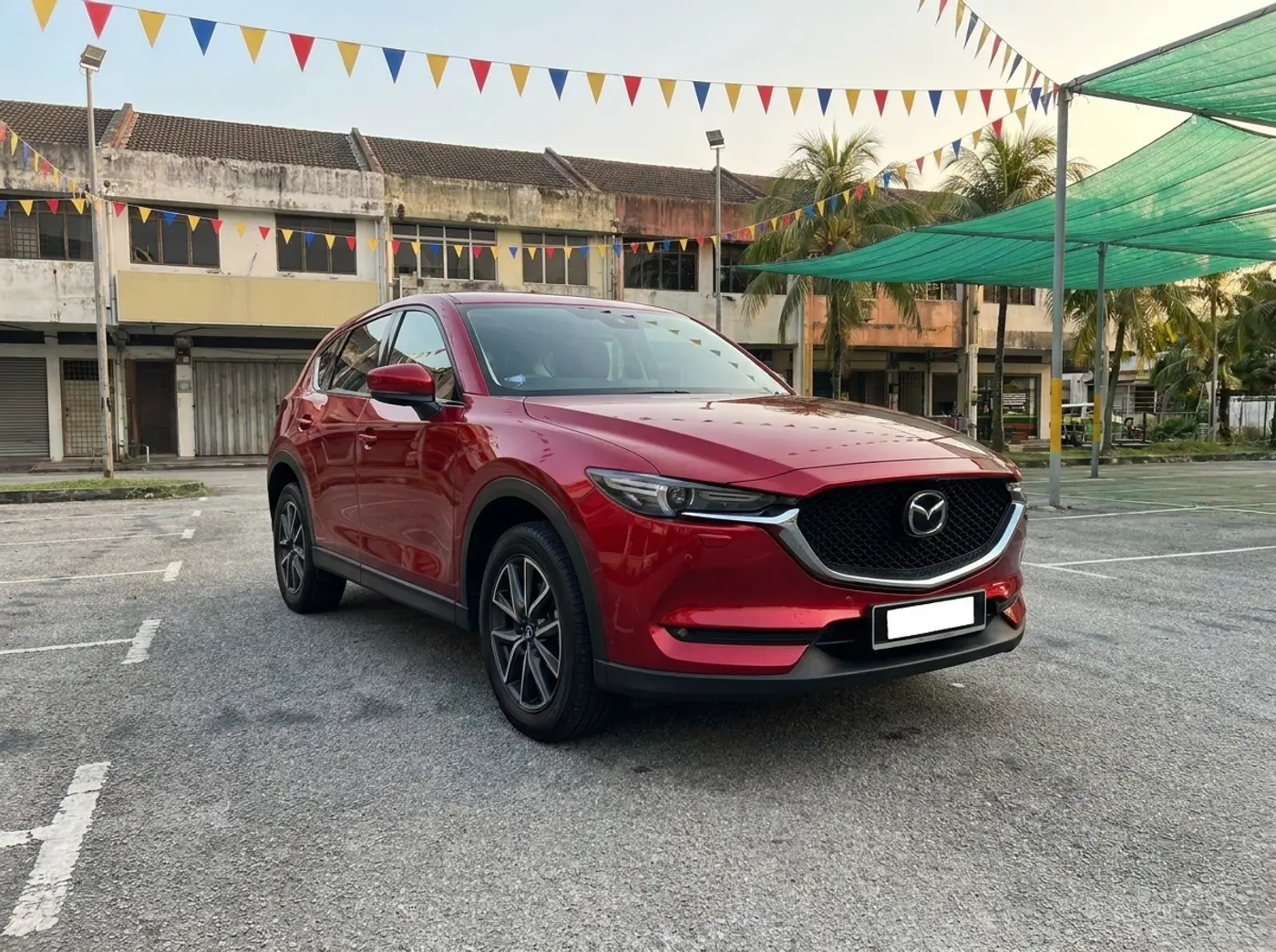 A red Mazda CX-5 on the used-car lot with two-storey shophouses behind