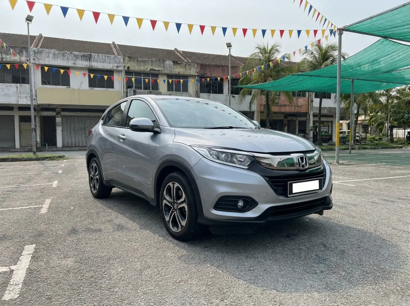 A silver Honda HR-V on the used-car lot under green shade nets and bunting