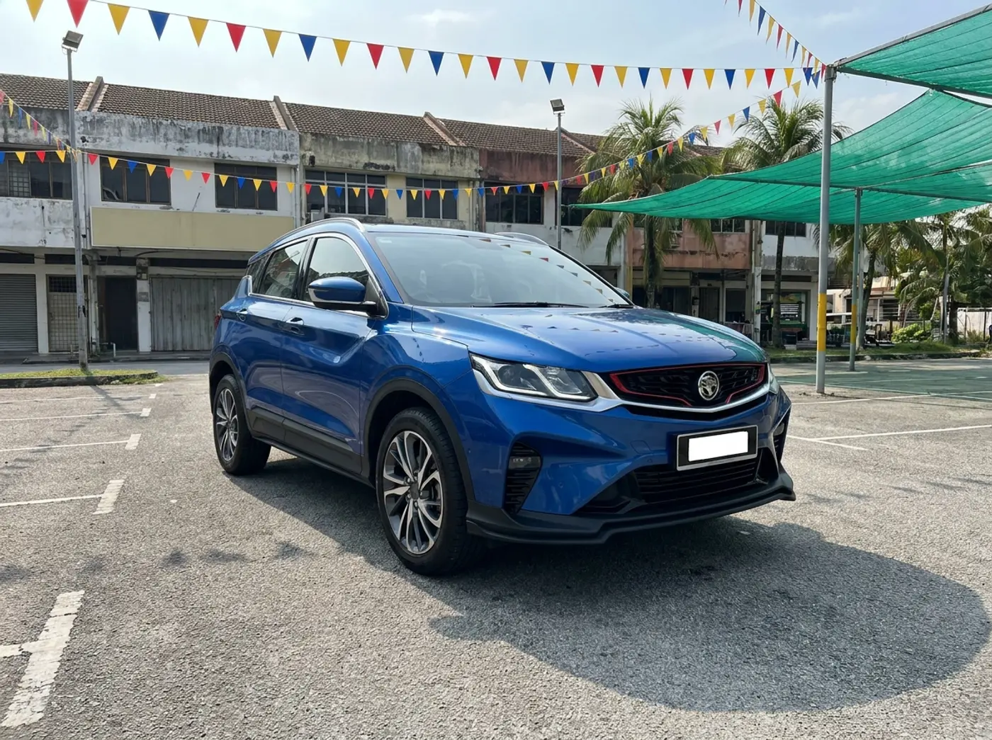 A marine blue Proton X50 parked on the KeretaKu Motors used-car lot in Cheras